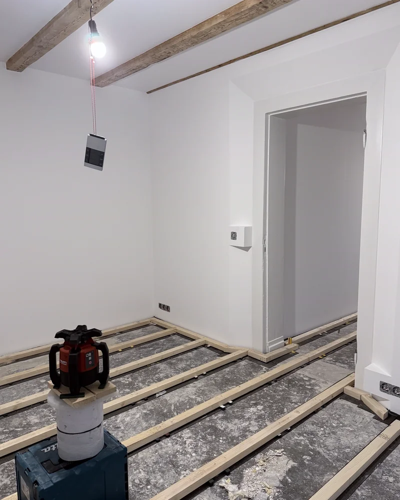 Sanierter Raum mit sichtbarer Balkendecke und neuen Lagerhölzern für den Fußboden