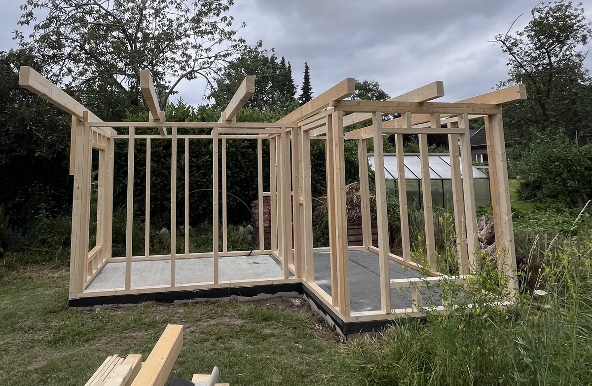 Holzständerrohbau eines Gartenhauses im Garten