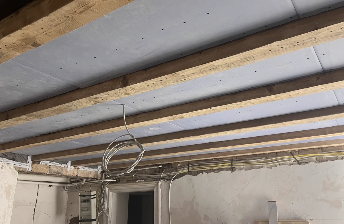 Deckenverkleidung mit Platten zwischen freigelegten Holzbalken